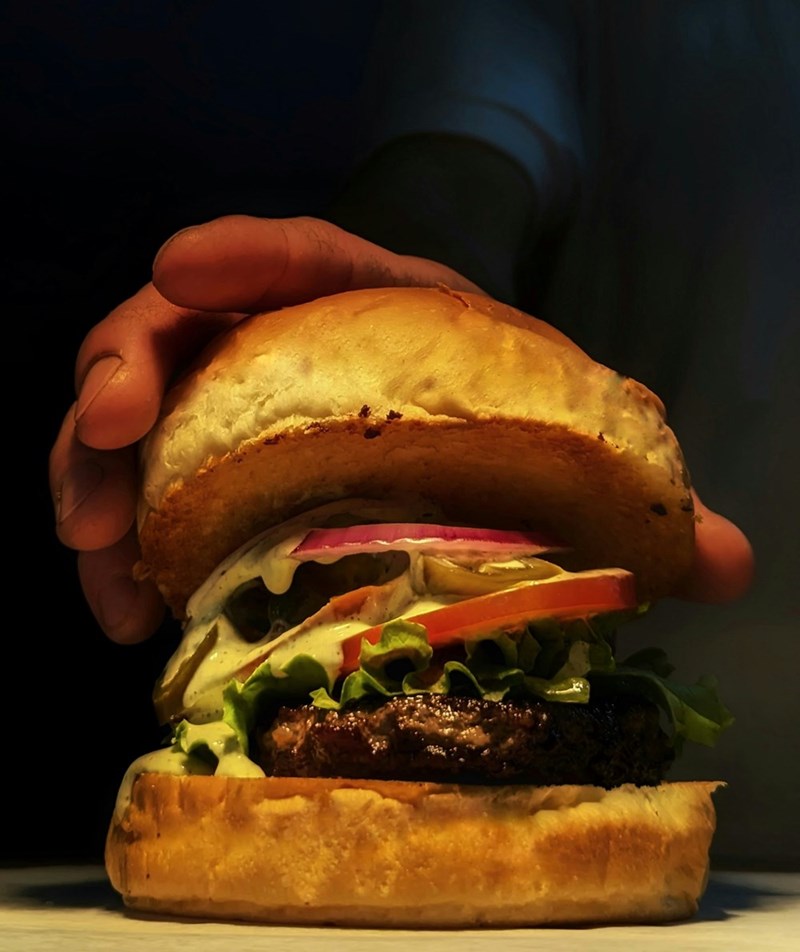 Man reaching for a large tasty burger