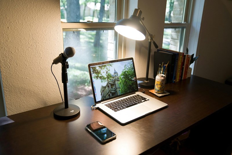 Microphone next to a macbook pro on a brown wooden table
