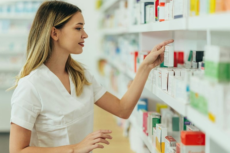 A female pharmacist stocks shelves in a pharmacy