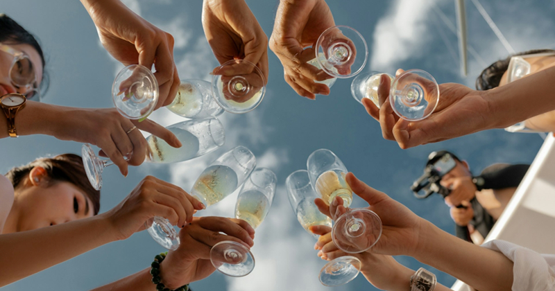 Underside of multiple people clinking champagne glasses