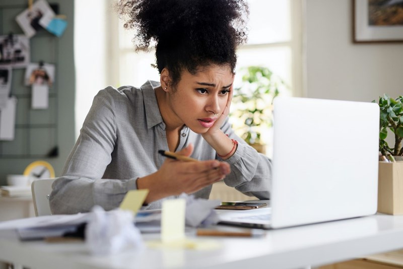 Frustrated young woman with laptop working indoors at home office