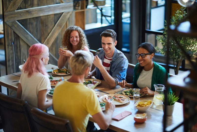 Group of 5 coworkers dine together at restaurant.