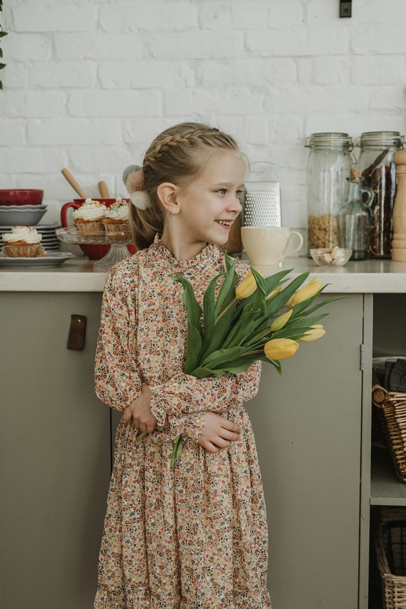 A little girl in a floral dress holding a bouquet of flowers