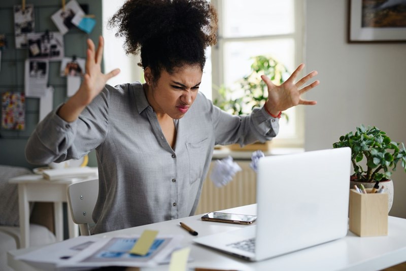 Woman throws up her hands in frustration after being fired from her remote-work job.
