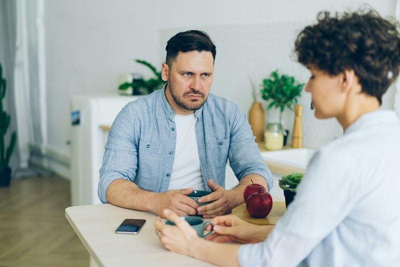 A man sitting at a table, talking to a woman