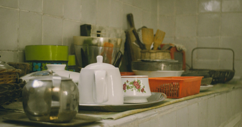 A kitchen counter crowded with various pieces of kitchenware