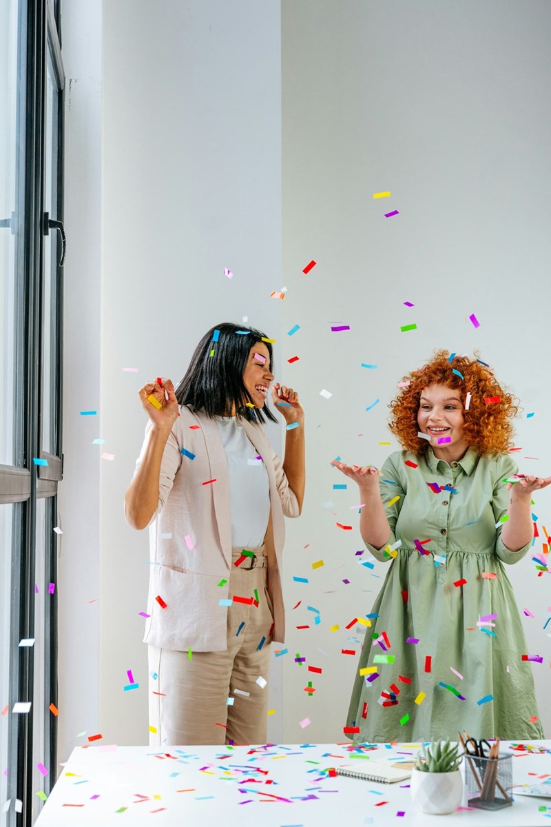 Employees throw confetti at office party.