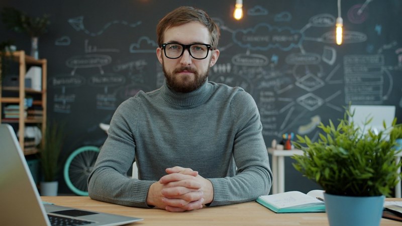 A frustrated man sits at his desk with his arms folded