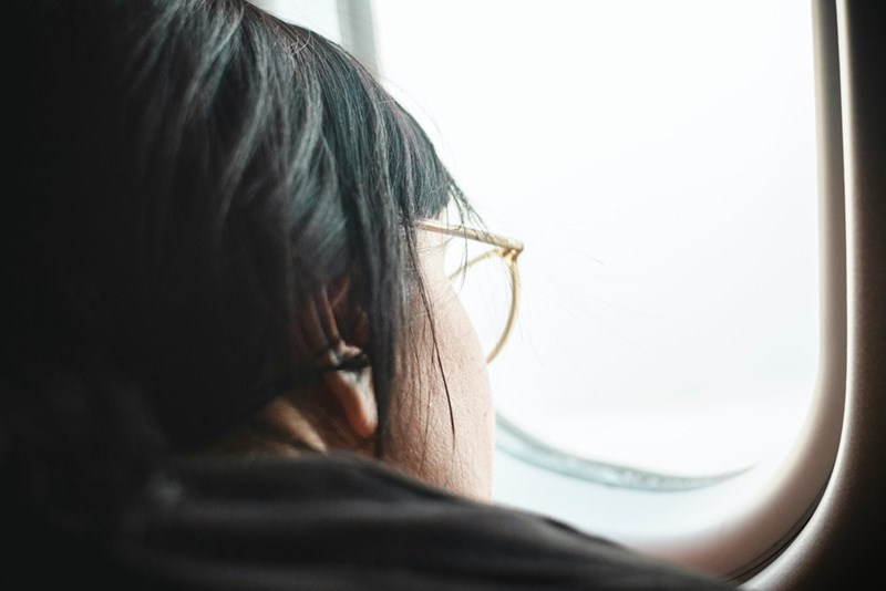 A woman looks outside an airplane window