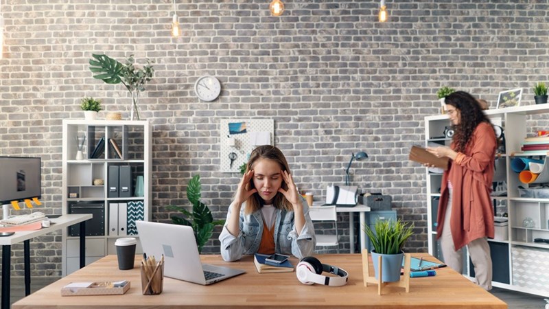 A stressed woman sitting at a table with a laptop computer