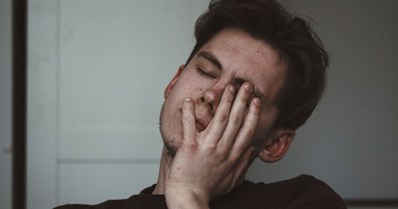 A man puts his head in his hands in frustration after learning about the HOA's trash sign.
