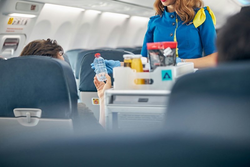 A flight attendant passes out food to the entitled passenger seated in front of the author.