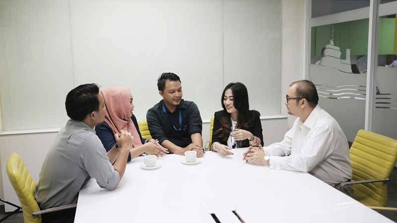 A group of people sit around a white table in an office