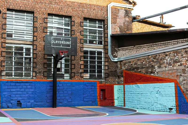 An outside school playground with a basketball hoop mounted against a brick wall.