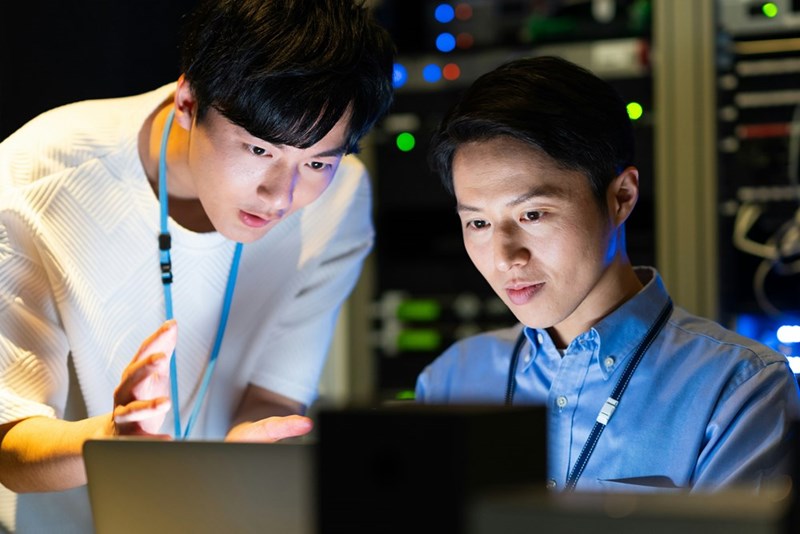 Tech workers discuss solutions to a problem that another employee left behind after quitting.