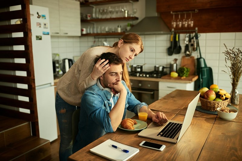 Pensive freelance worker and his wife reading and email on a computer while working at home
