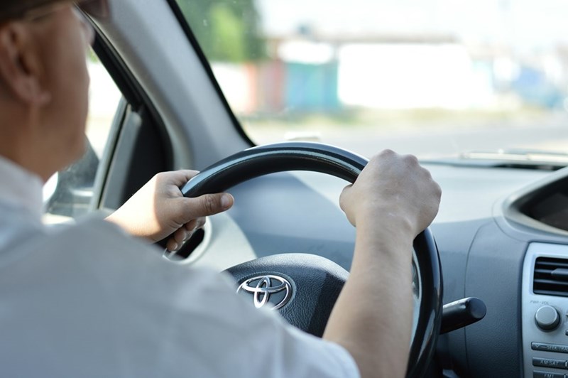 Man driving car, hands on the steering wheel.