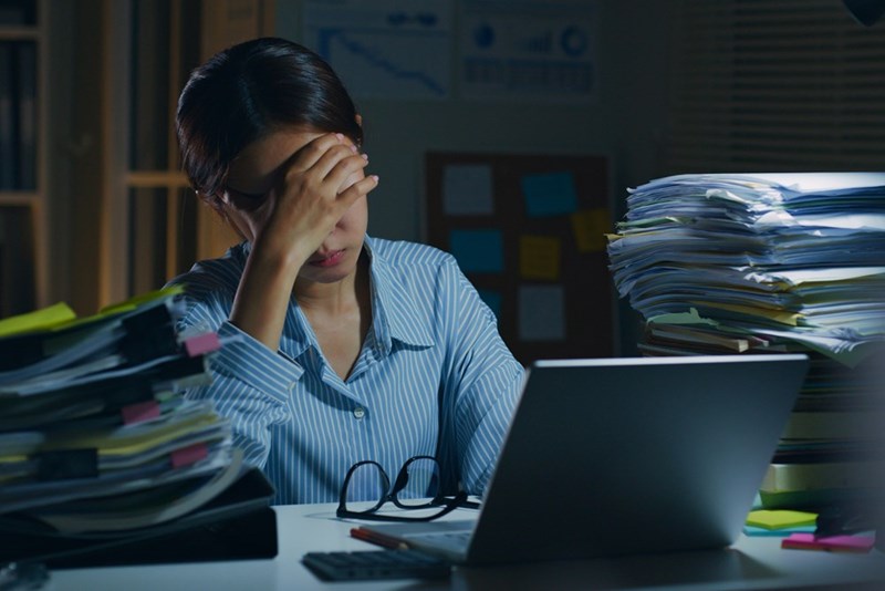 A female employee puts her head in her hands at her desk