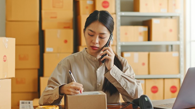 A woman working in a retail environment talks on the phone