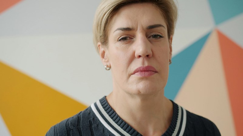 A woman with short blonde hair and a serious expression