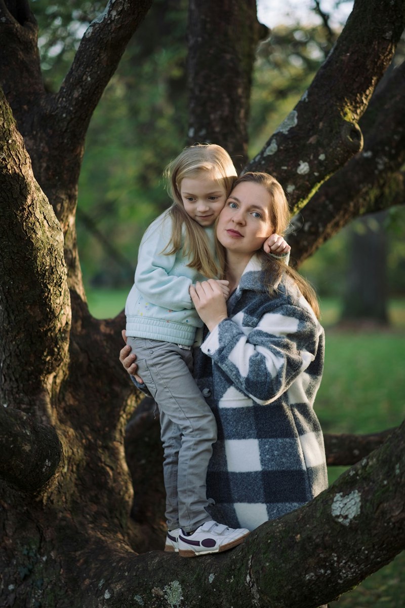Mom and daughter stand alongside their family tree.