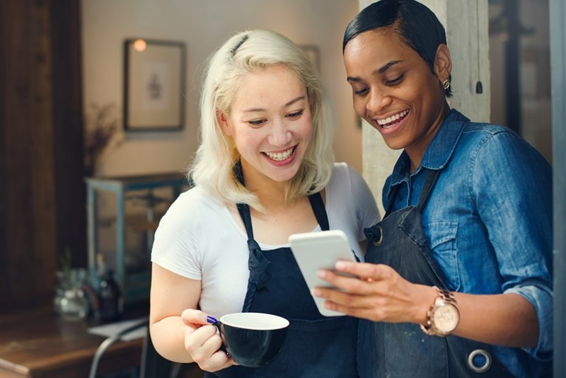 Two baristas looking at a phone while on their break from work