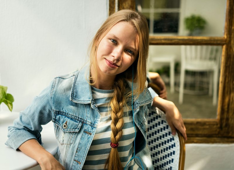 A young cheerful teenager looks at the camera