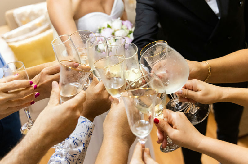 Couple and guests clinking glasses at a wedding, sharing a joyful toast.