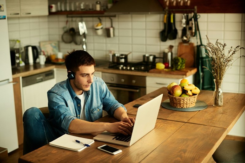 A remote employee works on his laptop while no longer having to meet with his manager during lunchtime.