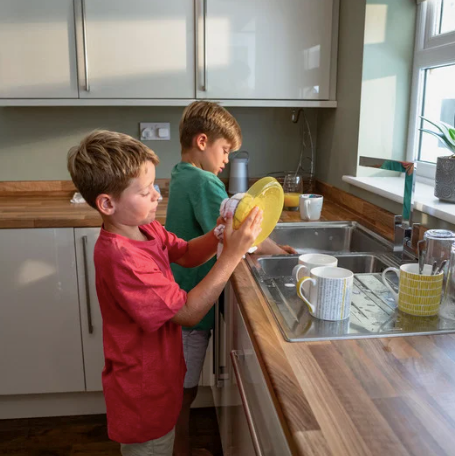 Two brothers washing the dishes together.