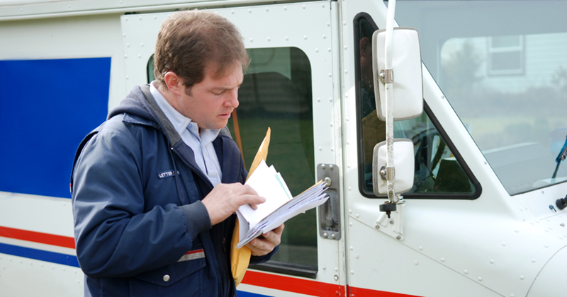 Mailman looking at a pile of letters for a resident. 