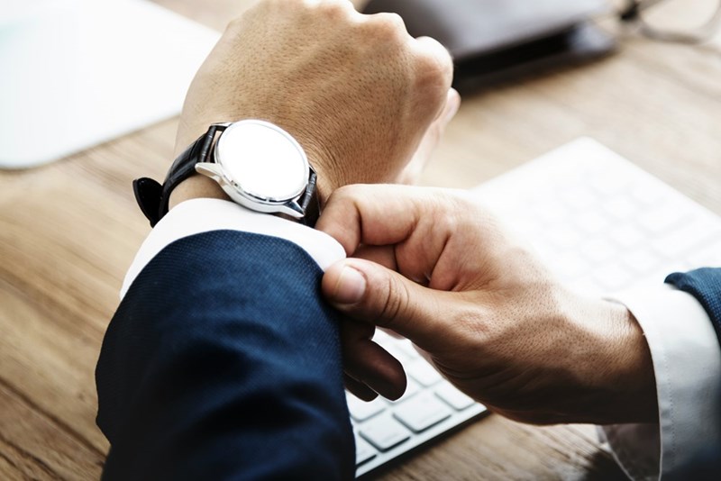 The employee checks his watch at his desk.