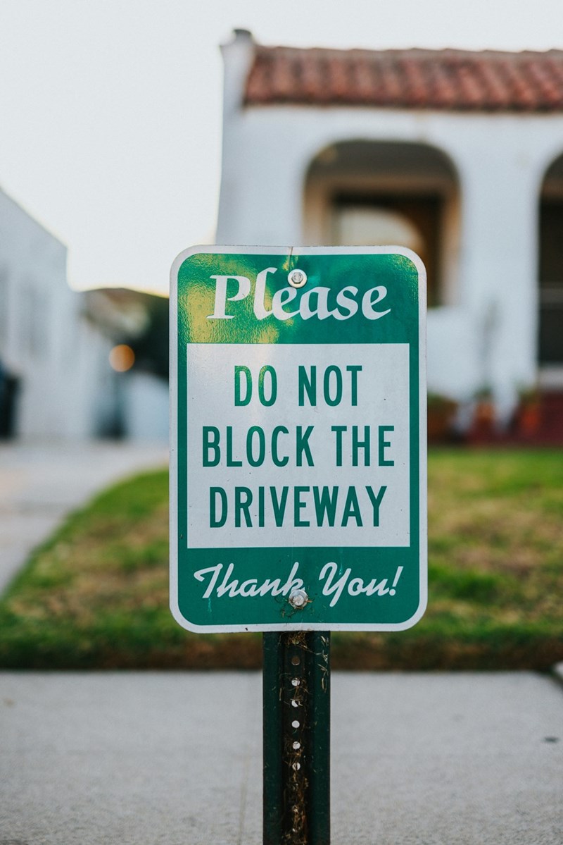 A sign on the street: Please DO NOT BLOCK DRIVEWAY.