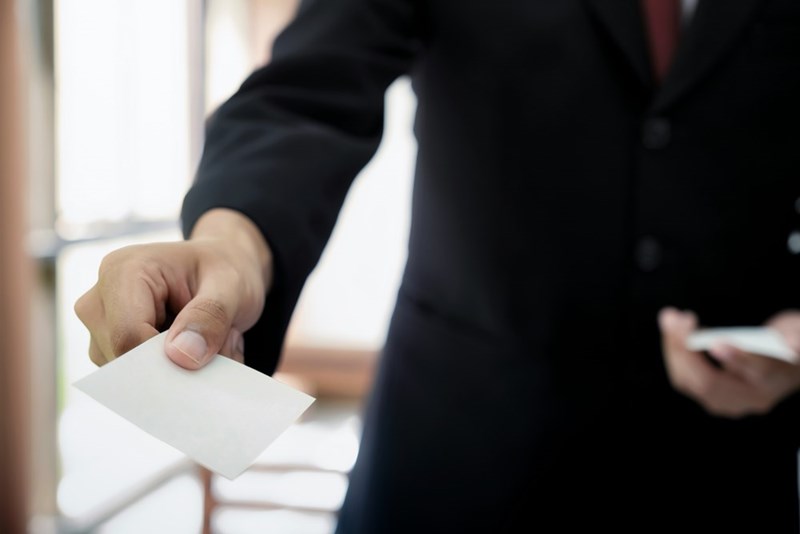 A businessman hands his business card to someone