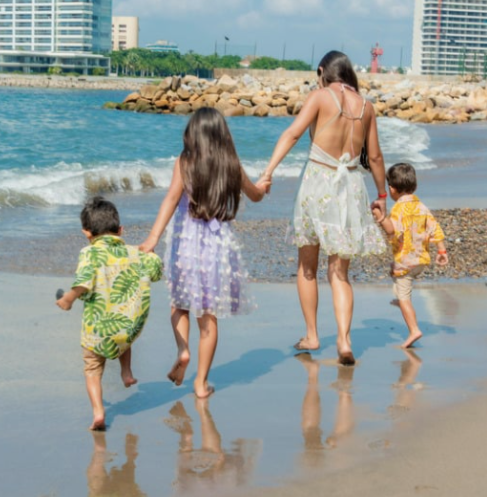 Mom walking with her kids on the beach while they enjoy a vacation.