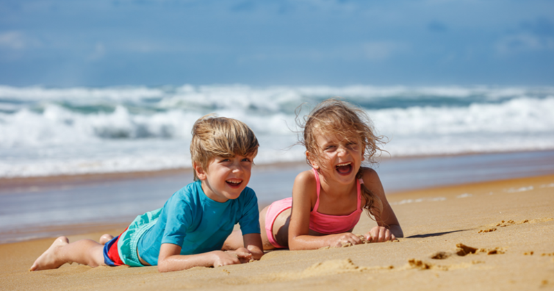 Kids playing alone on the beach in the summertime.