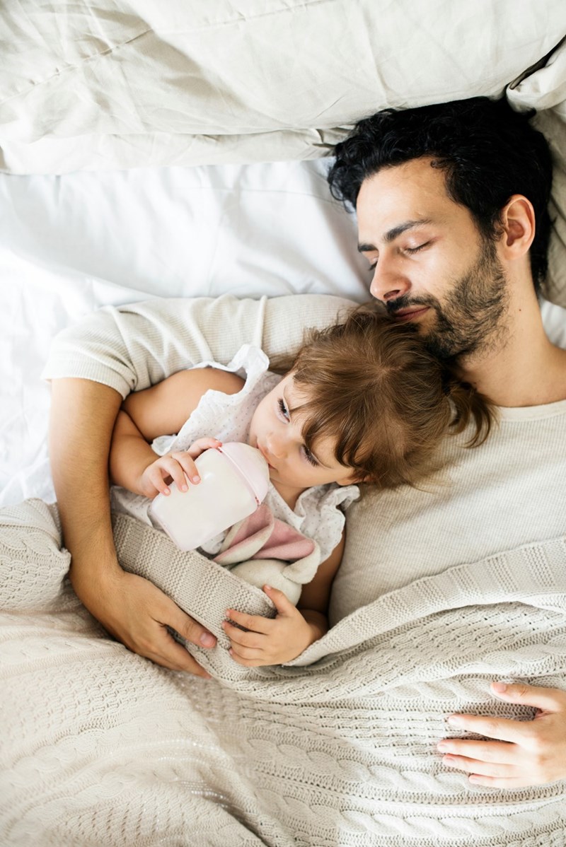 Father and daughter sleeping together on the bed