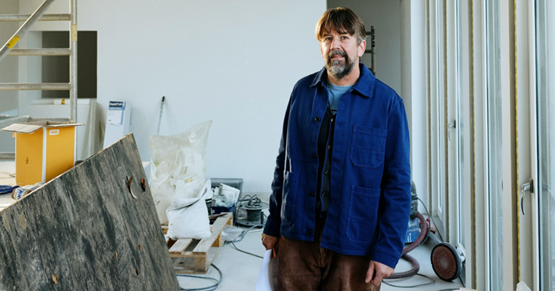 An older man stands in the middle of a building that is being renovated