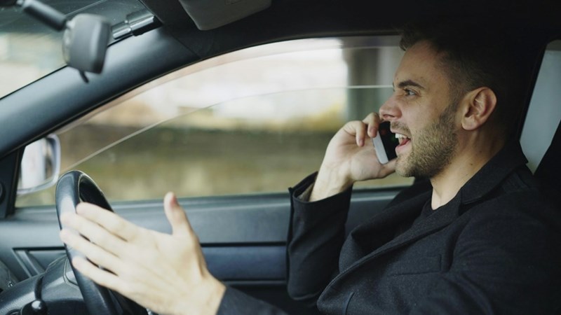 A man yells on the phone while seated in his car