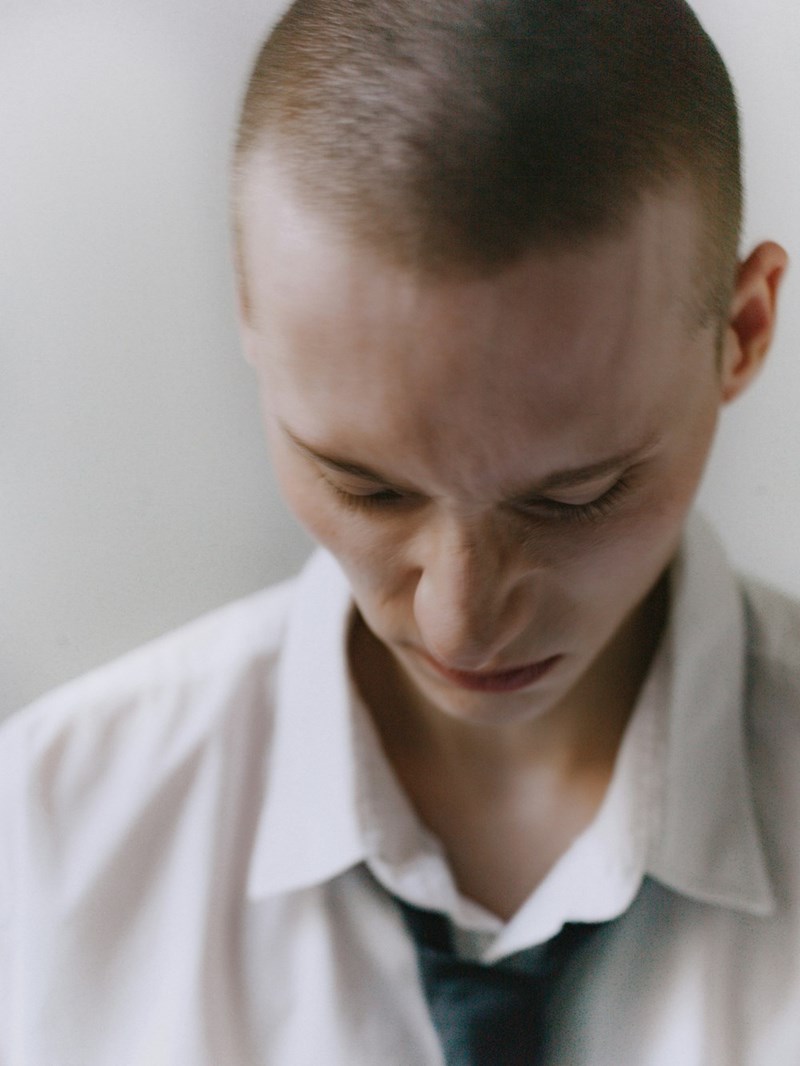 A person with a shaved head wearing a white shirt