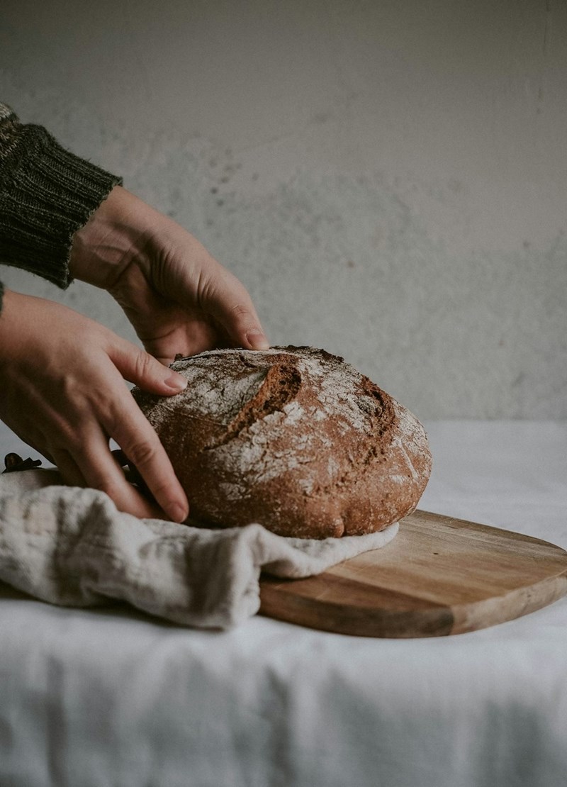 A baked loaf of sourdough is placed carefully on a table