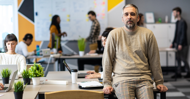 Man working in an open concept office with his coworkers.