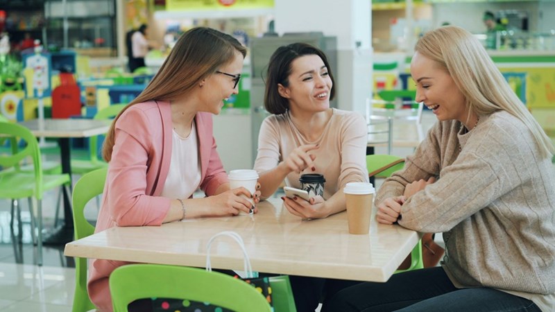 Three women laughing and talking at a table