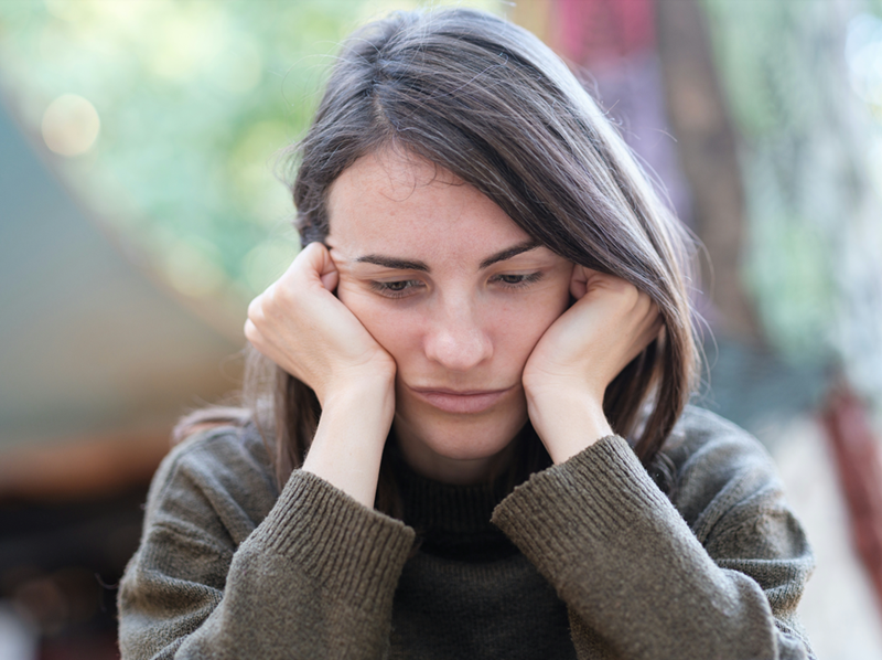 A young woman holds her head in her hands