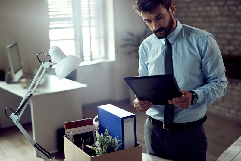 Worker packs up his belongings from desk after getting fired.