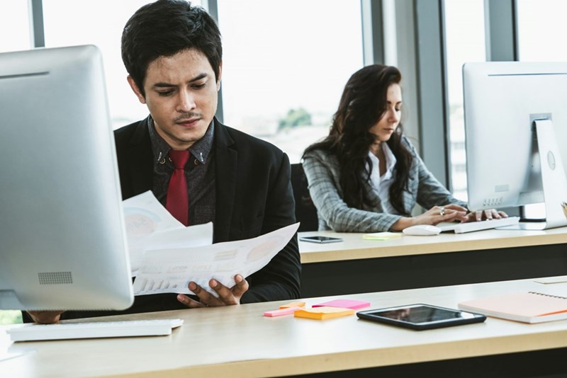 Employee looks at papers and realizes he's made a mistake.