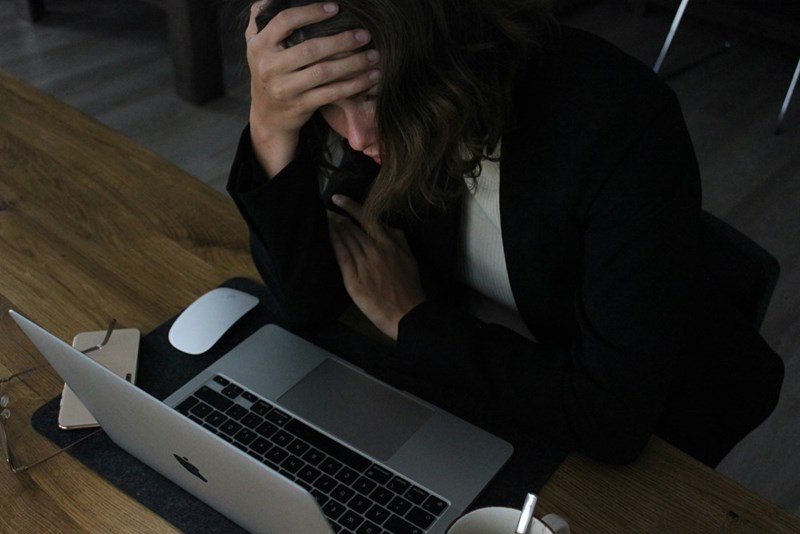 A woman in a black blazer sits on a chair at work