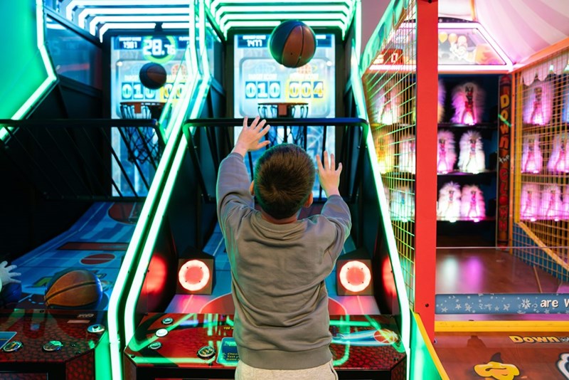Boy plays basketball arcade game