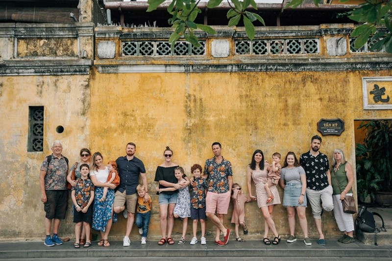 A group of people posing for a photo in front of a yellow building