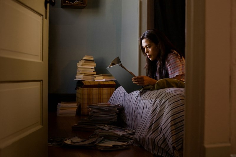 Girl reads a magazine in a room full of books